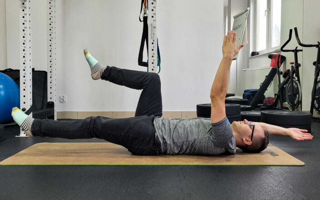 Mężczyzna wykonujący ćwiczenia na macie na sali gimnastycznej w trakcie fizjoterapii w Krakowie.